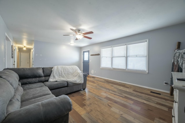 living room with visible vents, ceiling fan, baseboards, and wood-type flooring