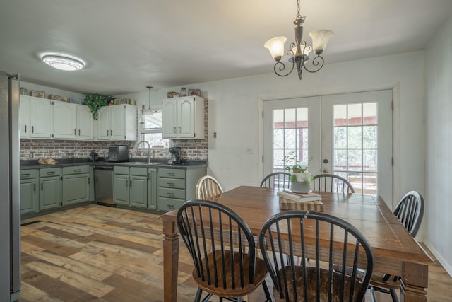 dining space with french doors, light wood-type flooring, and a chandelier