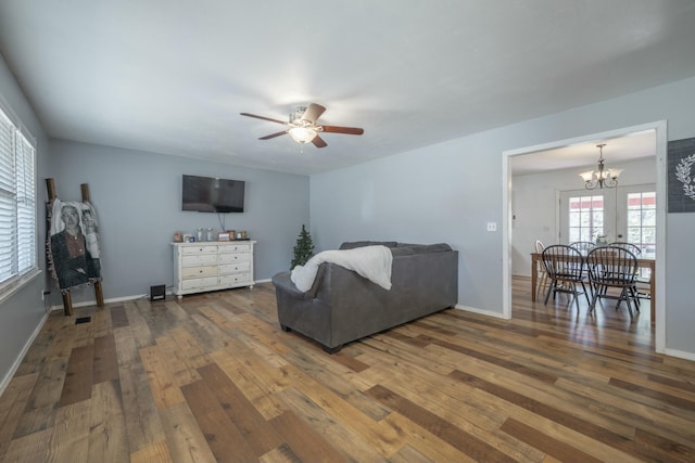 living room featuring baseboards, ceiling fan with notable chandelier, and hardwood / wood-style flooring