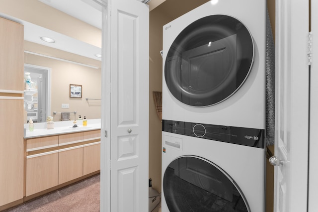 laundry room featuring laundry area, recessed lighting, a sink, stacked washer / drying machine, and light carpet