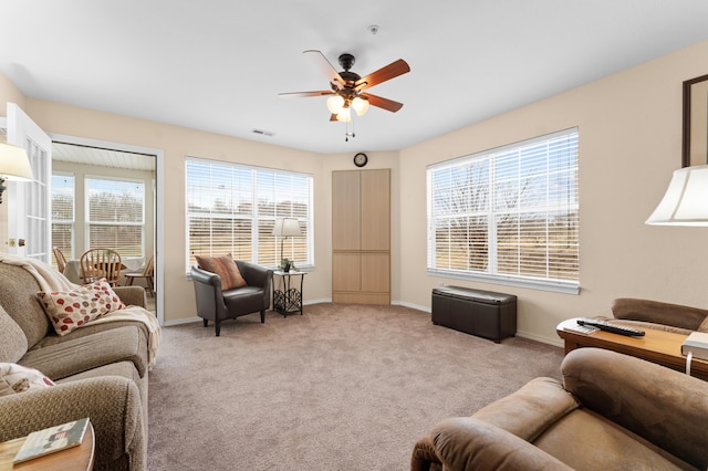 living room featuring light carpet, visible vents, baseboards, and ceiling fan