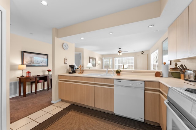 kitchen featuring light brown cabinetry, dishwasher, light carpet, and a sink