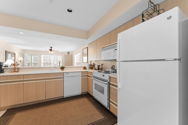 kitchen with light brown cabinets, white appliances, light countertops, and a sink