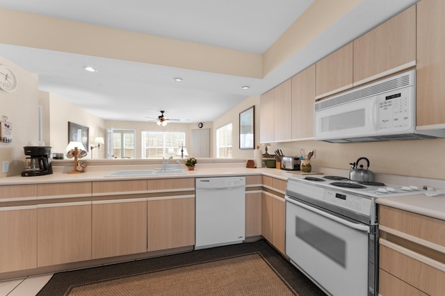 kitchen featuring light brown cabinetry, white appliances, light countertops, and a sink