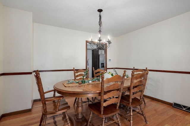 dining space with a chandelier, visible vents, light wood-style flooring, and baseboards