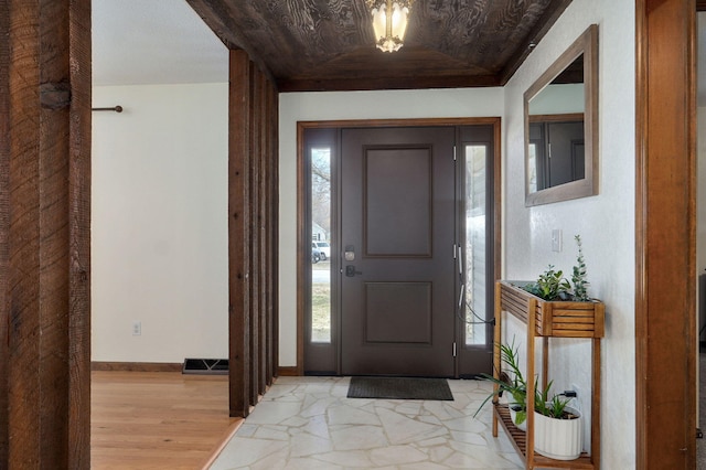 foyer with visible vents, a raised ceiling, light wood-type flooring, and baseboards