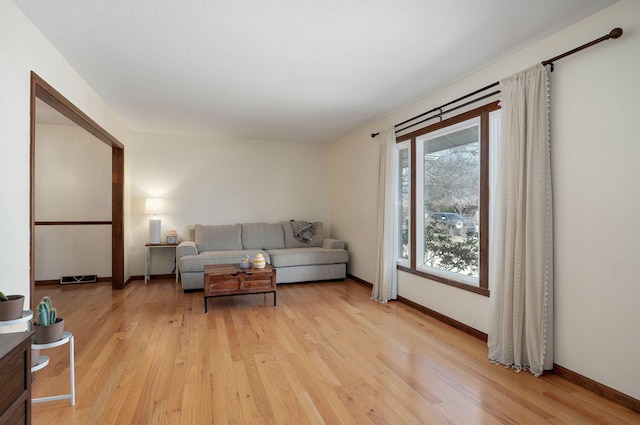 living room featuring visible vents, baseboards, and light wood-type flooring