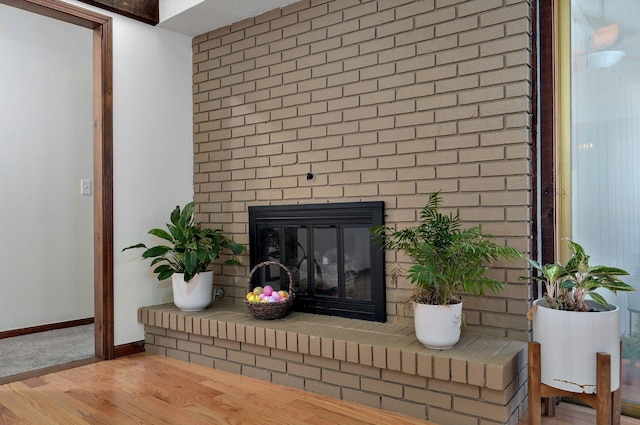 interior details featuring a brick fireplace, wood finished floors, and baseboards