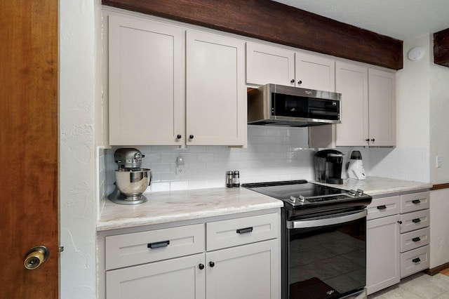 kitchen with backsplash, stainless steel microwave, range with electric cooktop, and white cabinetry