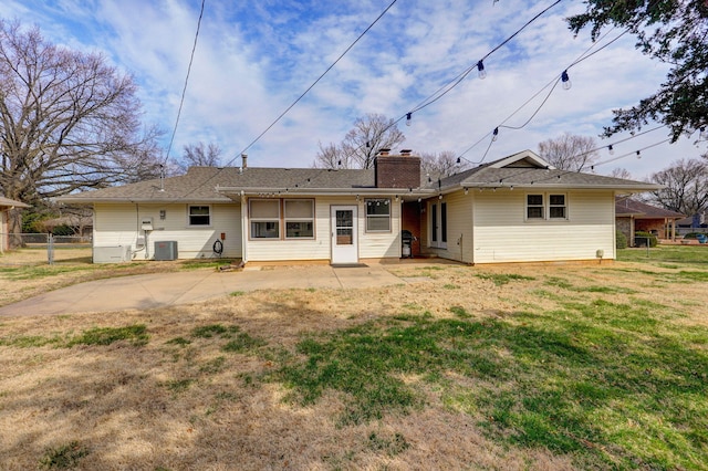 back of house featuring fence, central AC unit, a lawn, a chimney, and a patio