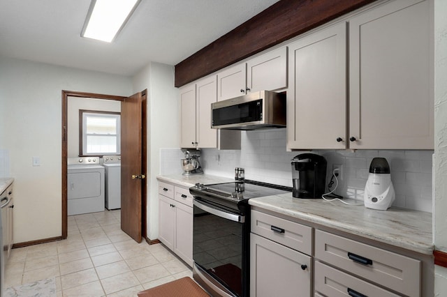 kitchen with washing machine and clothes dryer, stainless steel microwave, backsplash, light countertops, and range with electric stovetop