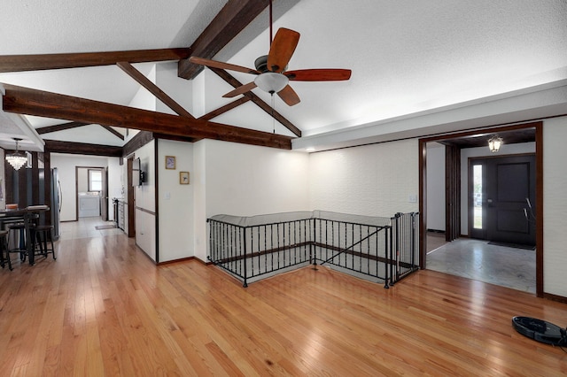 interior space featuring lofted ceiling with beams, washer / clothes dryer, light wood-style floors, a textured ceiling, and ceiling fan with notable chandelier