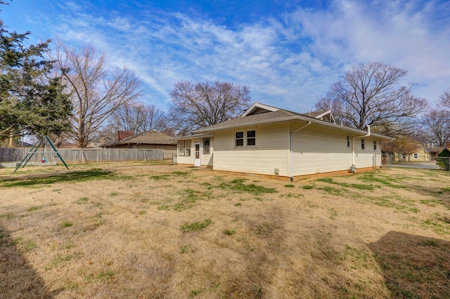 back of property featuring a yard, fence, and a playground