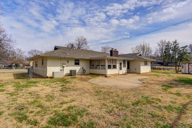 back of house featuring a gate, cooling unit, fence, a chimney, and a lawn