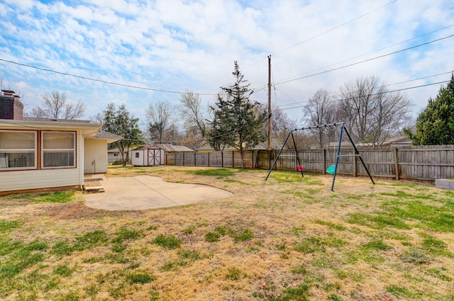 view of yard featuring a storage unit, a fenced backyard, a playground, an outdoor structure, and a patio area