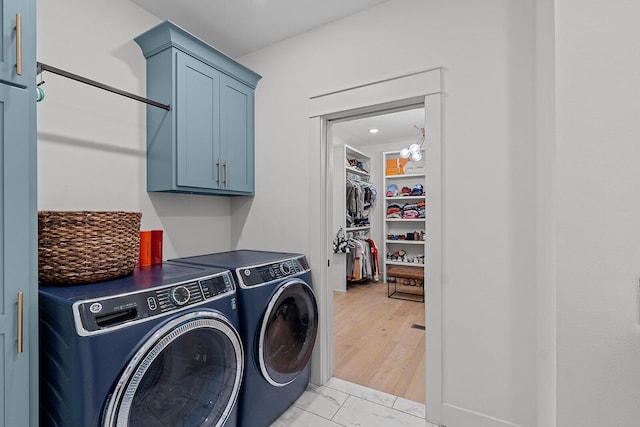 clothes washing area with cabinet space, marble finish floor, and washing machine and clothes dryer