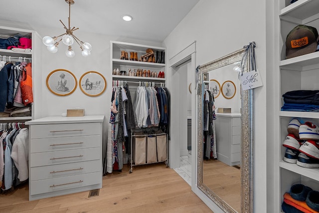 walk in closet featuring washer / dryer, a notable chandelier, and light wood-style flooring