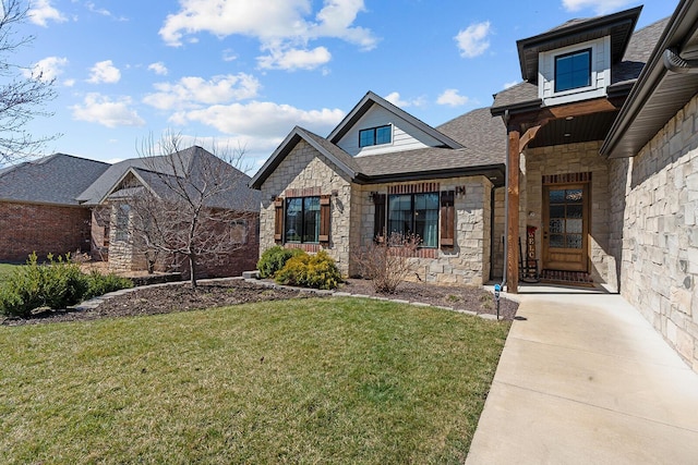 view of front of property featuring stone siding, a front yard, and roof with shingles