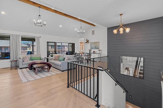 living room with beam ceiling, a notable chandelier, and light wood-style flooring