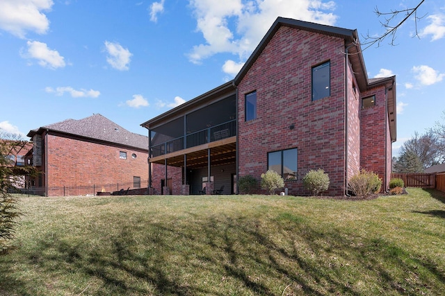 rear view of house with a yard, brick siding, a fenced backyard, and a sunroom