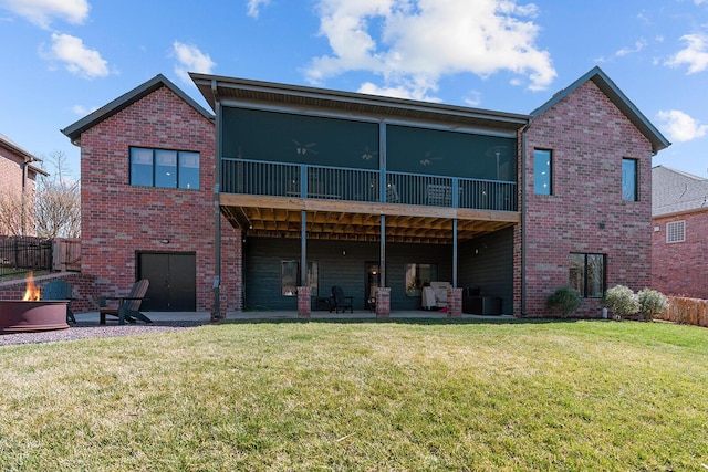 back of house featuring brick siding, a lawn, an outdoor fire pit, and a patio