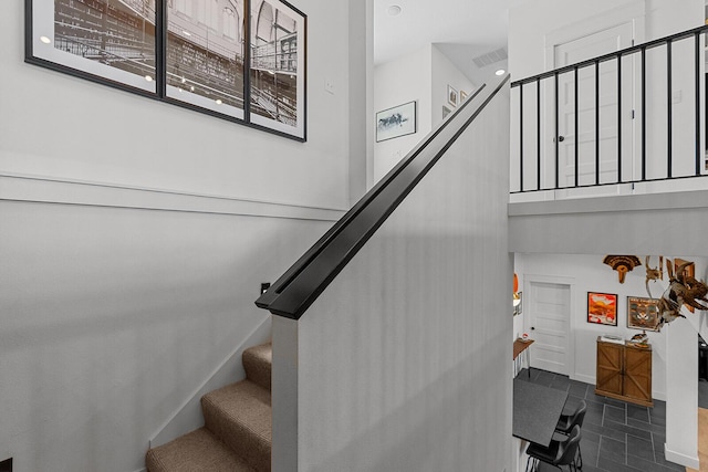 stairs with baseboards, visible vents, and a towering ceiling