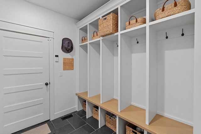 mudroom with baseboards and dark tile patterned floors