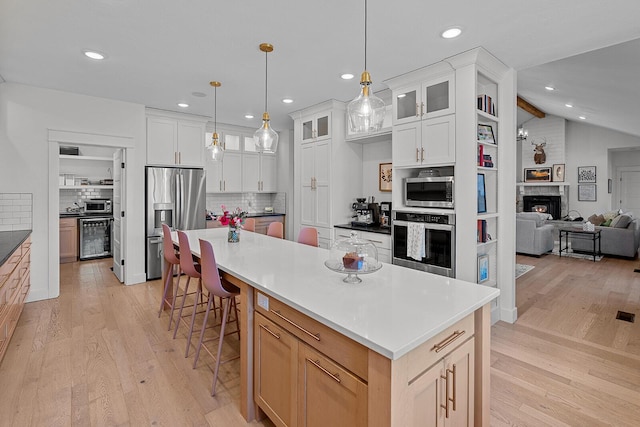 kitchen featuring light wood-style flooring, beverage cooler, decorative backsplash, appliances with stainless steel finishes, and glass insert cabinets