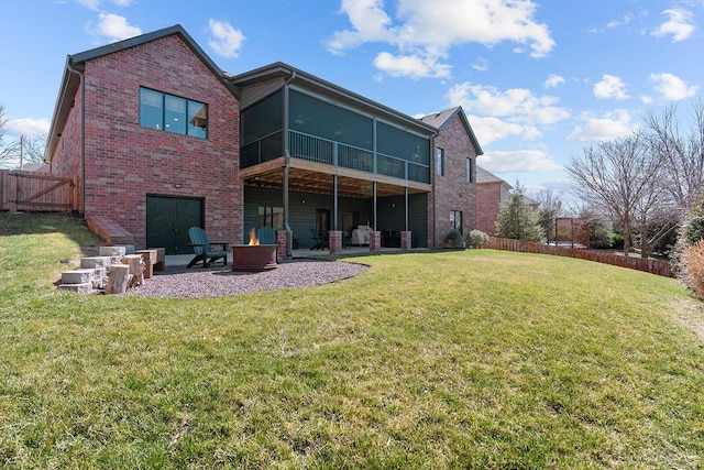 back of property featuring a lawn, fence, a fire pit, brick siding, and a patio area