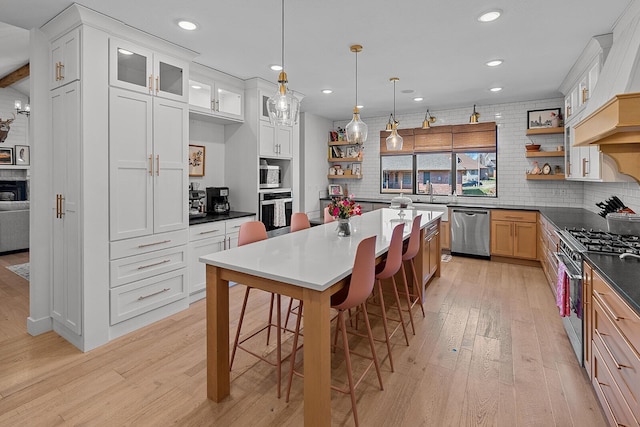 kitchen featuring open shelves, a kitchen breakfast bar, appliances with stainless steel finishes, and light wood-style flooring