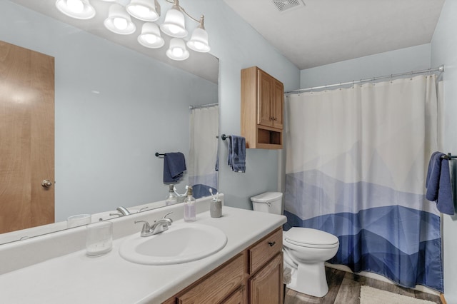 bathroom with vanity, toilet, wood finished floors, and visible vents