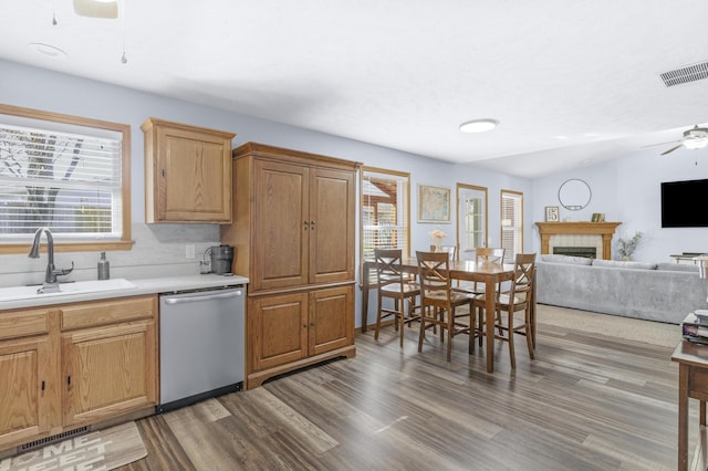 kitchen with visible vents, ceiling fan, dishwasher, a fireplace, and a sink