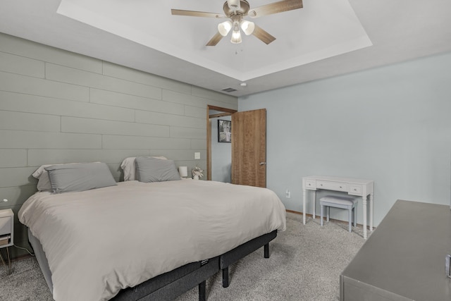 bedroom with a tray ceiling, carpet, visible vents, and ceiling fan