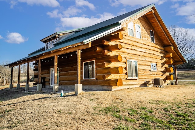 back of property featuring an outdoor structure, log siding, central AC, and metal roof