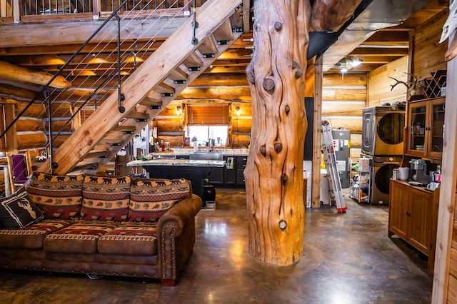 unfurnished living room with log walls, stacked washer / drying machine, and a sink