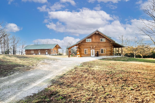 view of front of property with a front lawn, log exterior, and driveway