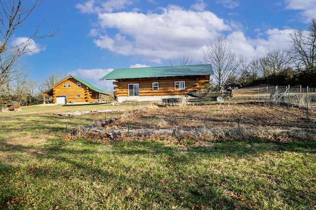 back of property with a garage, log exterior, a yard, and metal roof