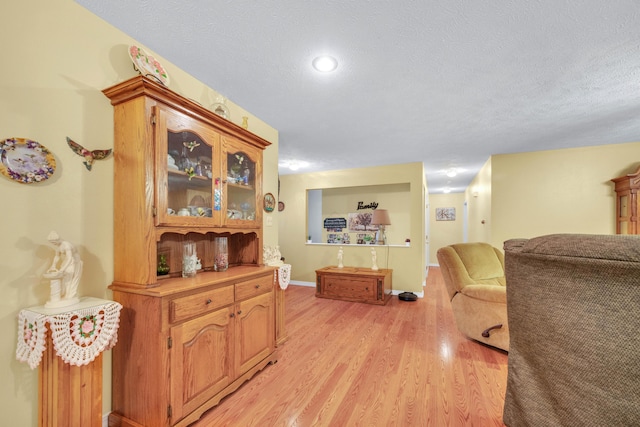 interior space with baseboards, light wood-style floors, and a textured ceiling