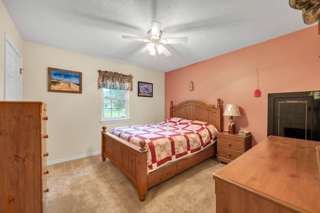 bedroom featuring baseboards, light colored carpet, ceiling fan, and a textured ceiling