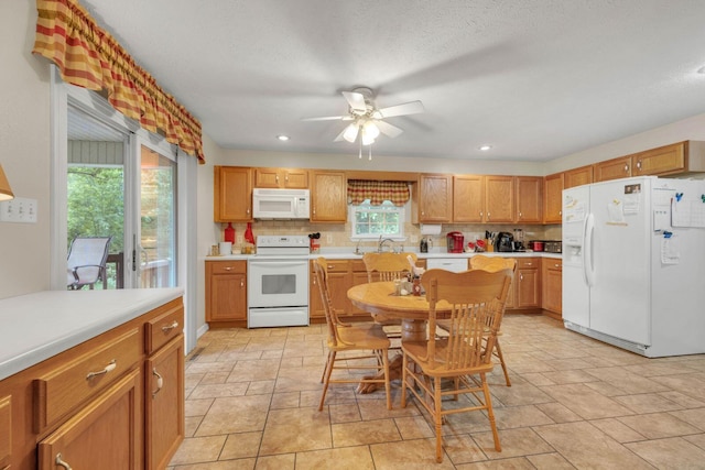 kitchen with a ceiling fan, a sink, tasteful backsplash, white appliances, and light countertops