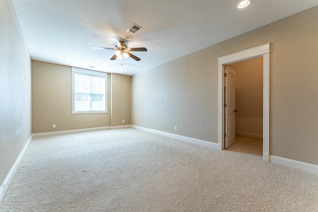 empty room featuring visible vents, baseboards, light colored carpet, and ceiling fan