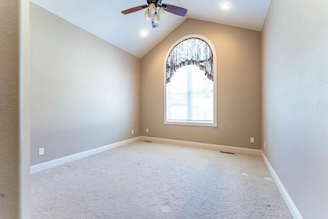 carpeted spare room with visible vents, baseboards, lofted ceiling, and a ceiling fan