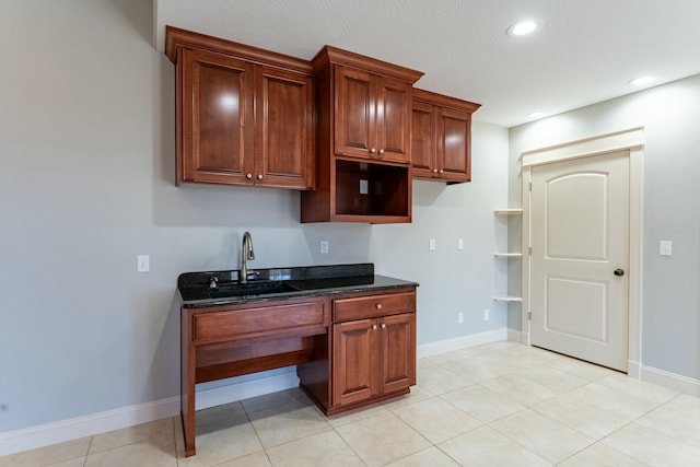 kitchen featuring recessed lighting, dark stone countertops, baseboards, and a sink