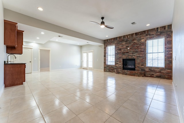 unfurnished living room featuring light tile patterned floors, visible vents, brick wall, and ceiling fan