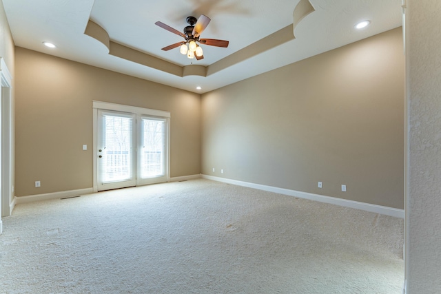 unfurnished room featuring baseboards, ceiling fan, light carpet, recessed lighting, and a raised ceiling