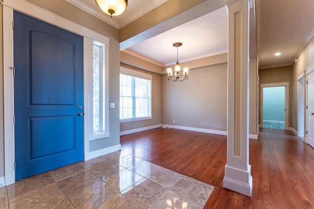 entrance foyer with a notable chandelier, wood finished floors, baseboards, and ornamental molding