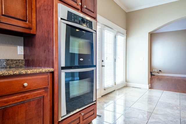 kitchen featuring arched walkways, plenty of natural light, double oven, and crown molding