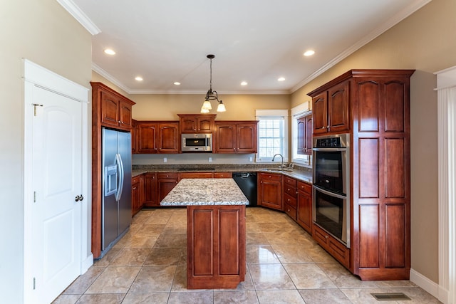 kitchen featuring visible vents, a kitchen island, a sink, hanging light fixtures, and stainless steel appliances