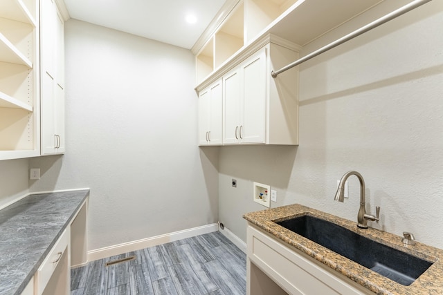 laundry area featuring light wood-style flooring, a sink, cabinet space, baseboards, and hookup for an electric dryer