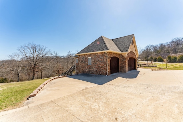 view of home's exterior with brick siding, concrete driveway, roof with shingles, a lawn, and a garage